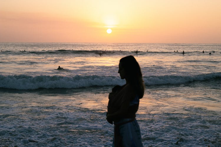 Woman With Baby On Beach At Sunset