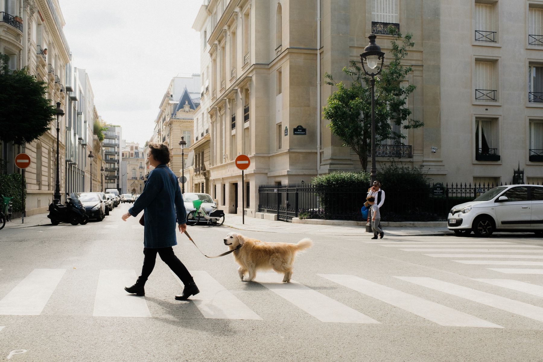 Femme traversant une rue parisienne avec son golden retriever en laisse