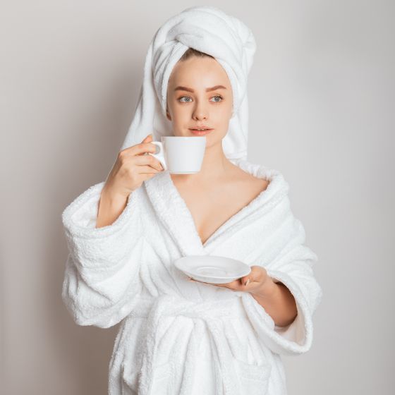 A person in a white robe holding a cup of morning coffee. Photo by Dmitriy Steinke on Pexels.