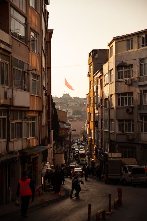 Free A vibrant street scene in Istanbul with people and a distant flag at sunset, capturing urban life. Stock Photo