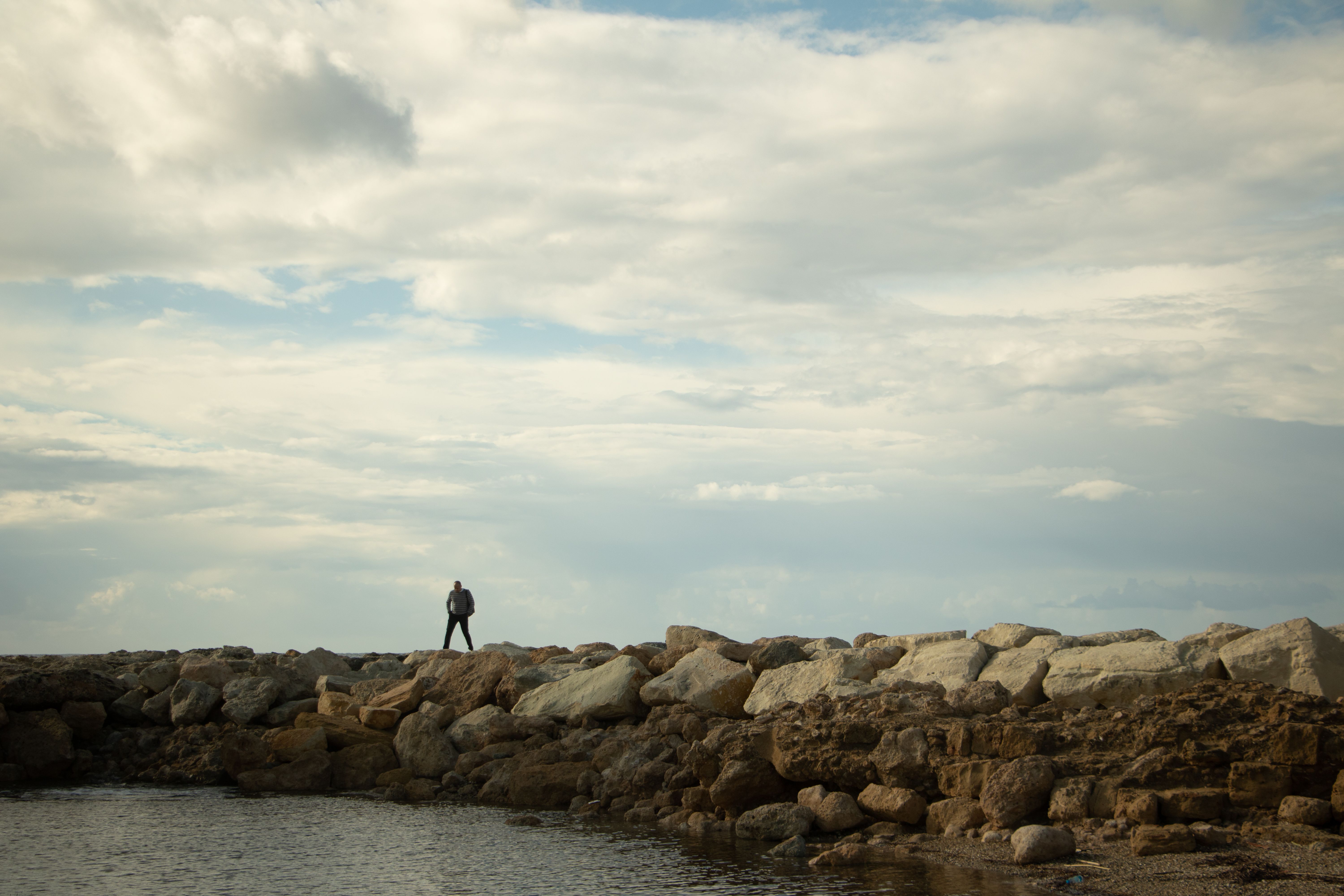 A person standing on rocks near the water · Free Stock Photo