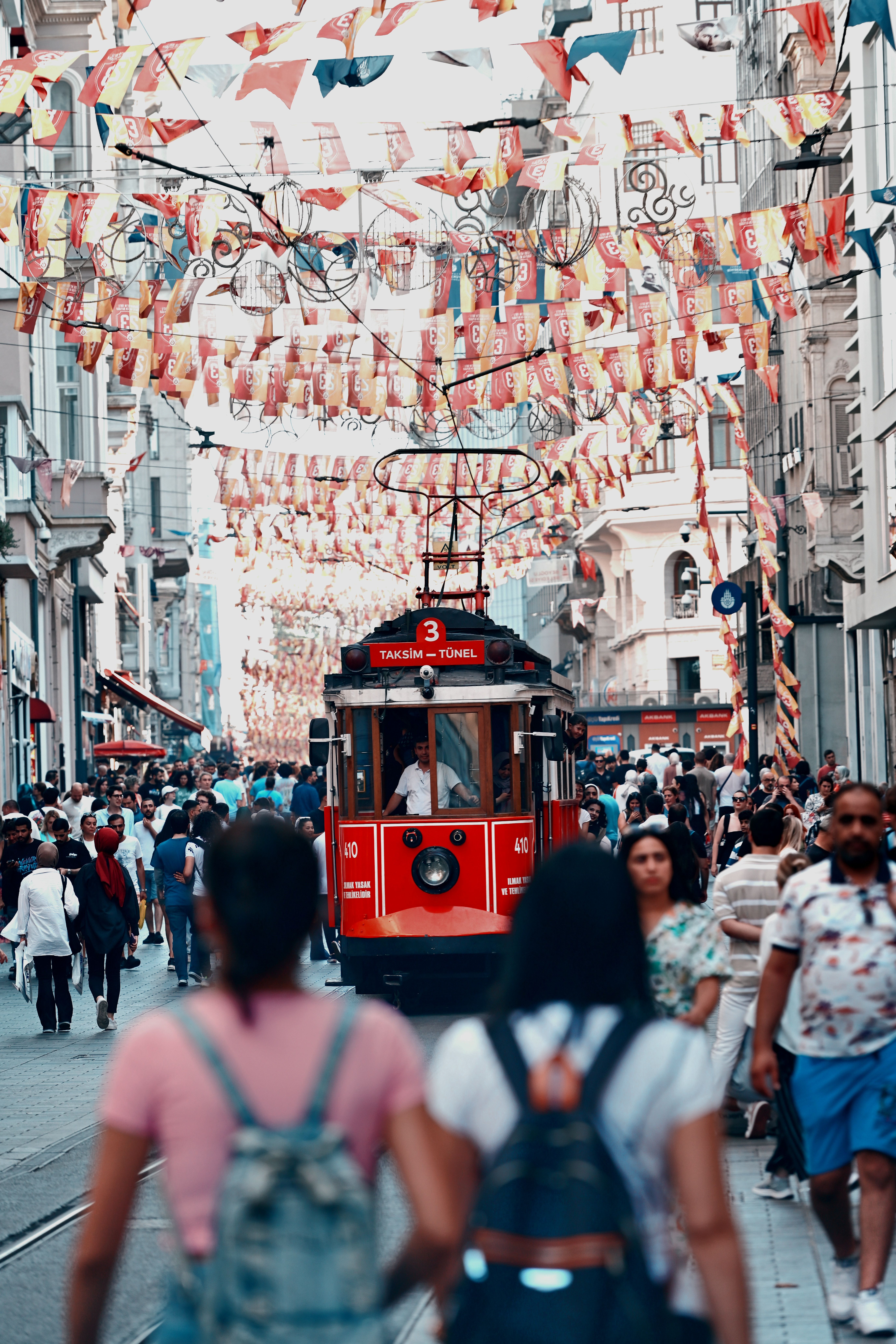 A red tram is traveling down a crowded street · Free Stock Photo
