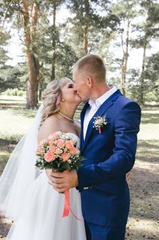 Bride and groom share a kiss in a beautiful outdoor summer setting.