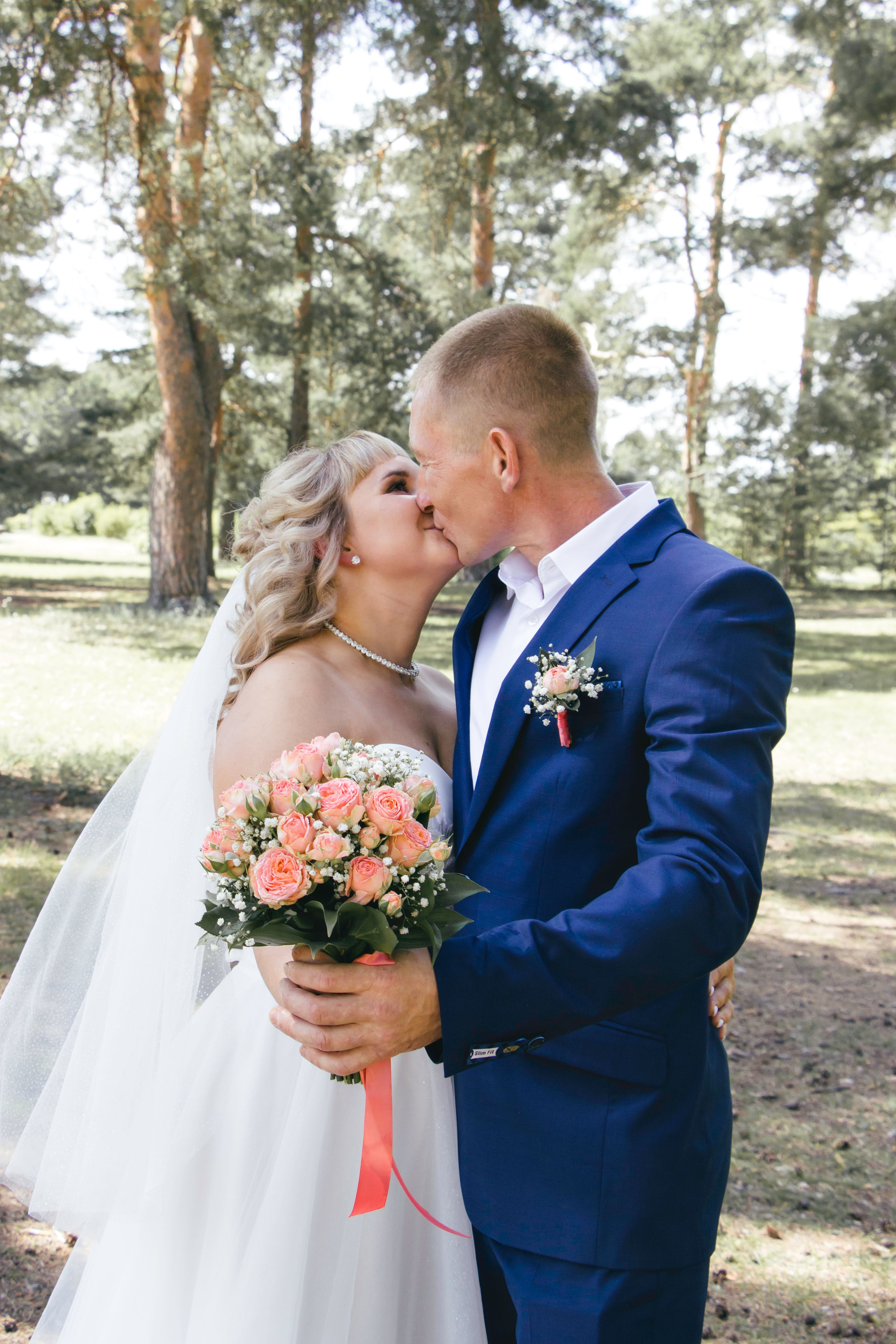 A bride and groom kiss in the woods · Free Stock Photo