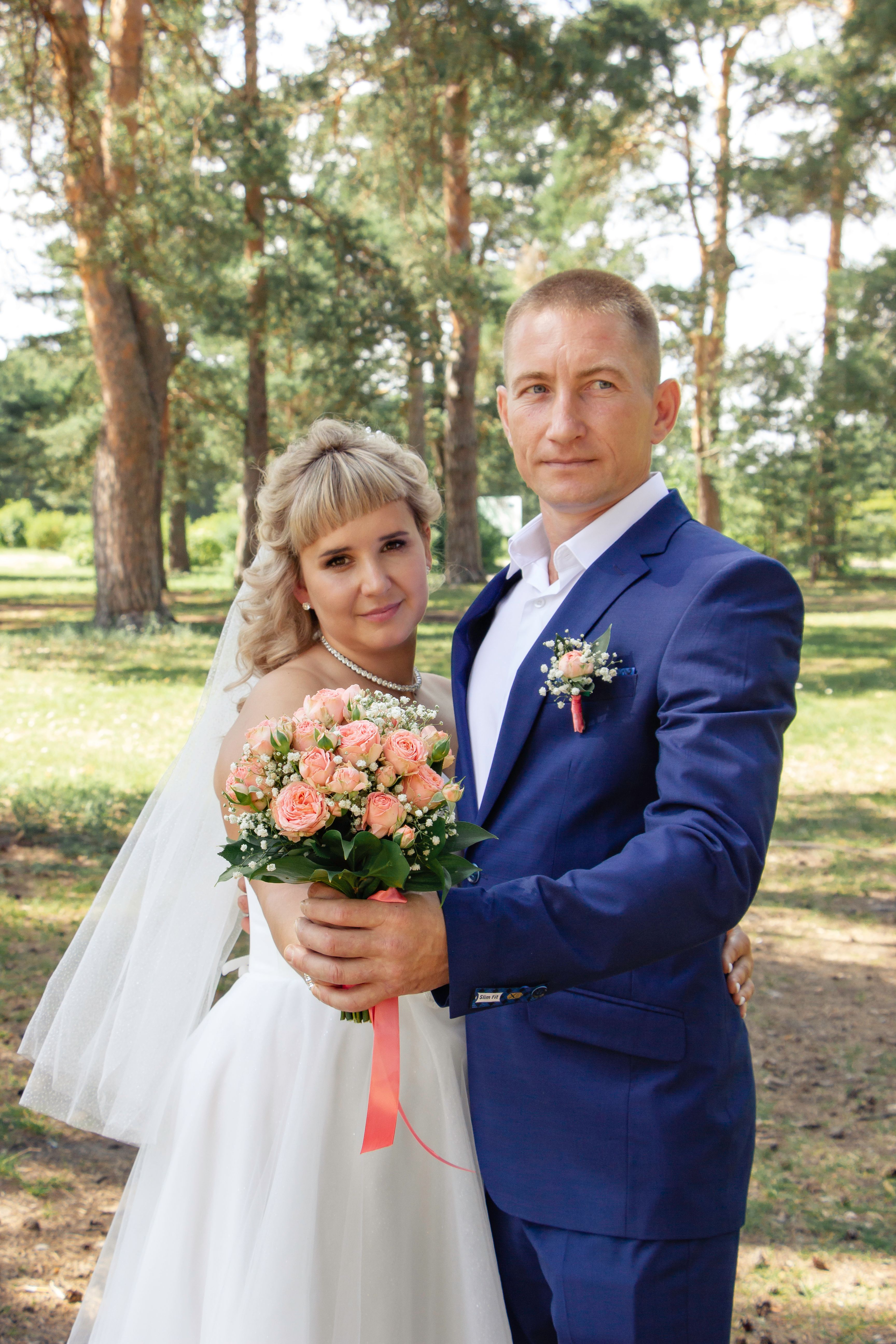 A bride and groom pose for a photo in the woods · Free Stock Photo