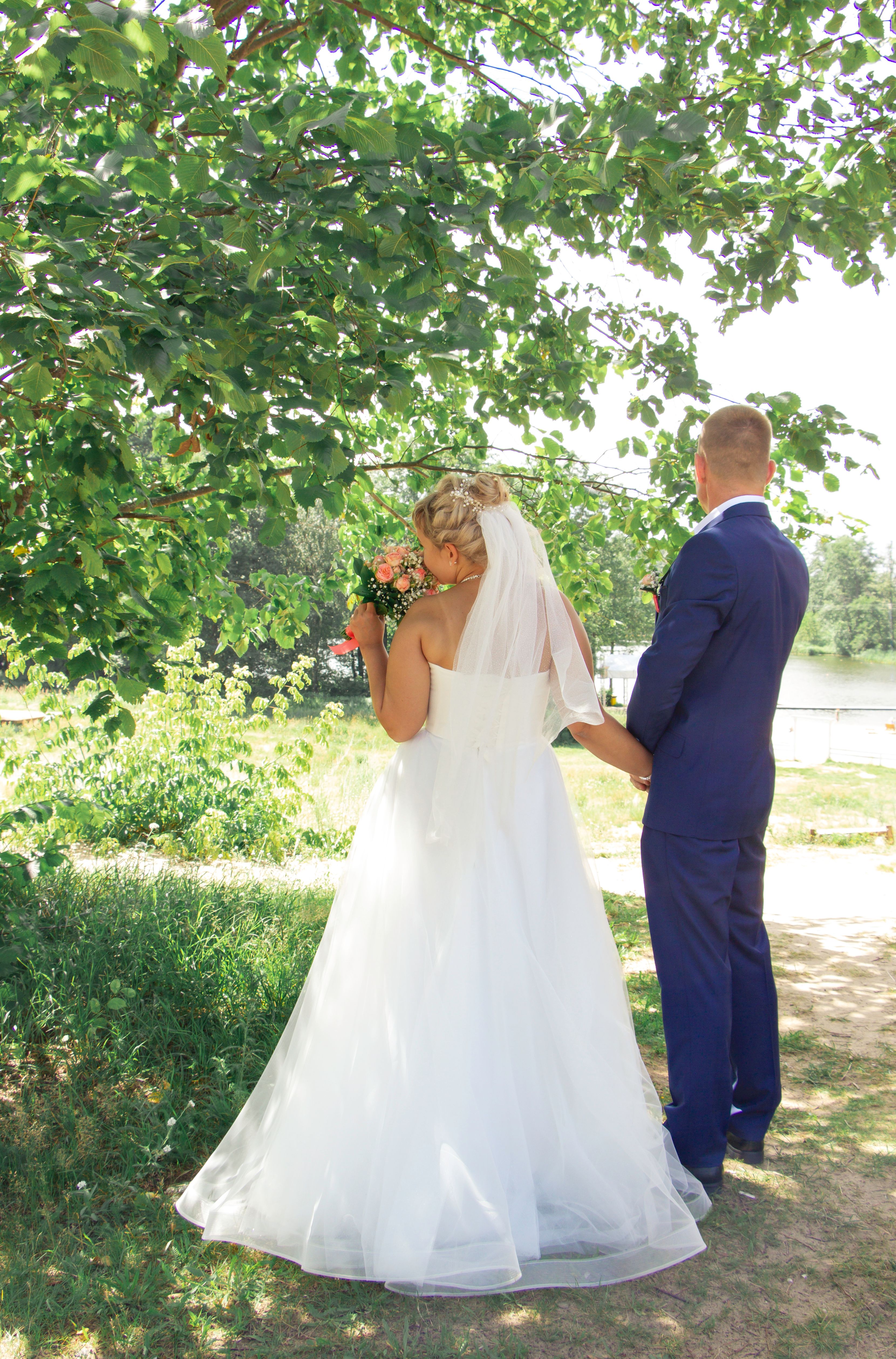 A bride and groom standing under a tree · Free Stock Photo