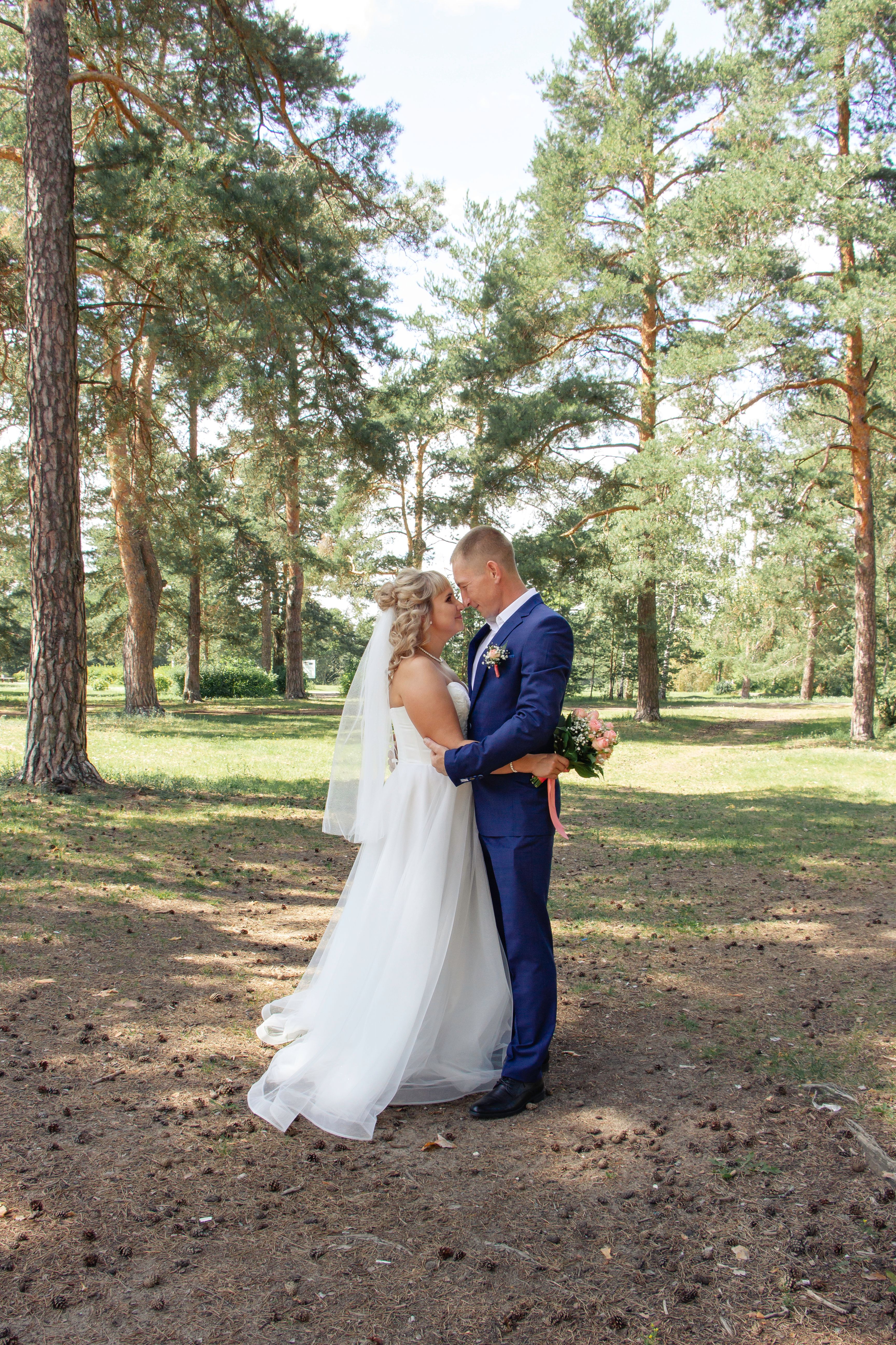 A bride and groom standing in the woods · Free Stock Photo
