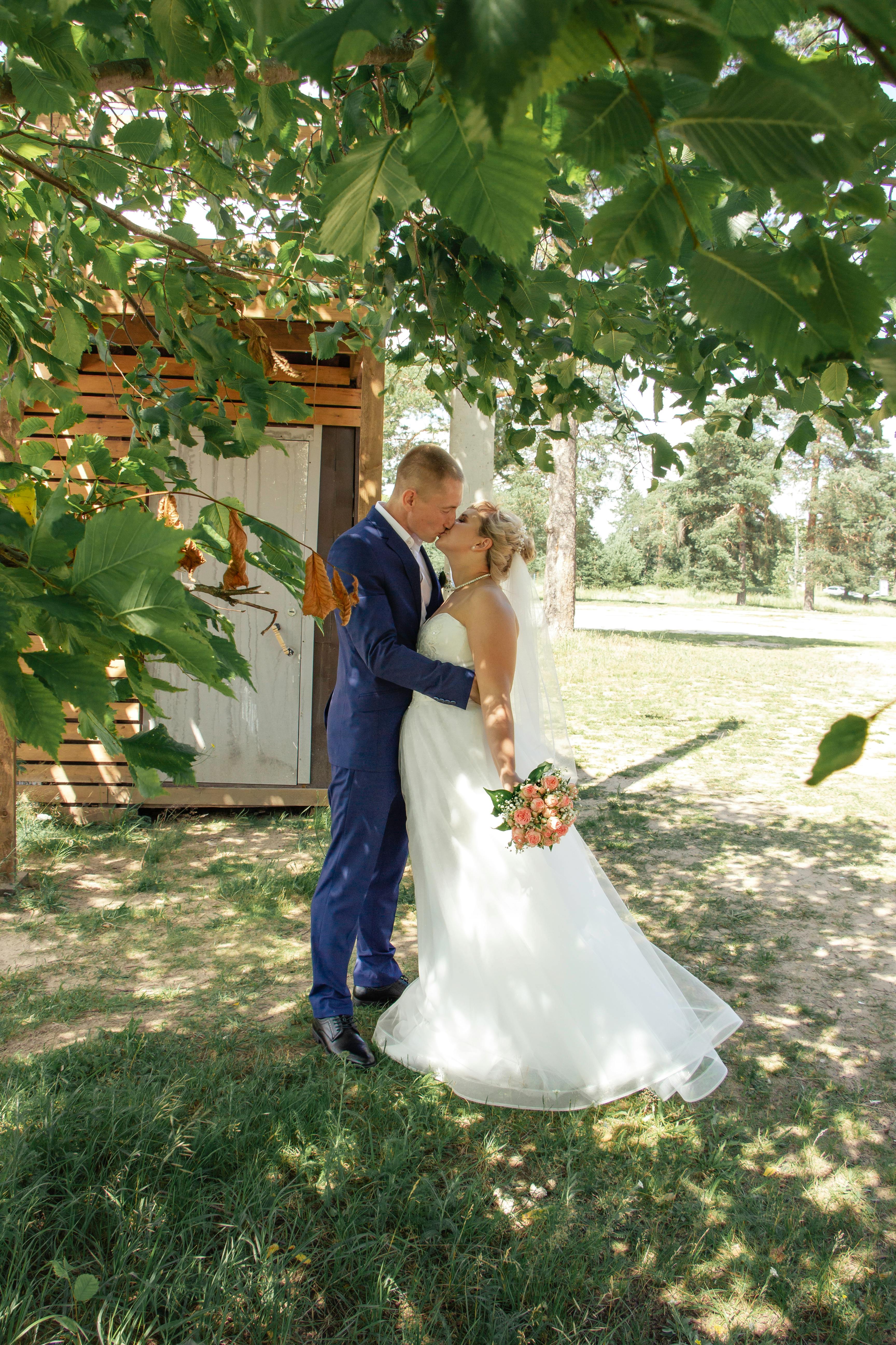 a bride and groom standing under a tree