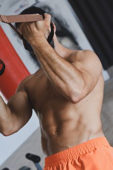 Muscular man using resistance bands during workout, showcasing strength and fitness.