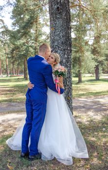 A loving couple embracing during their outdoor wedding in a scenic forest park.