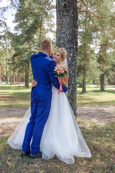Bride and groom share a loving embrace outdoors, capturing a romantic moment in a park setting.