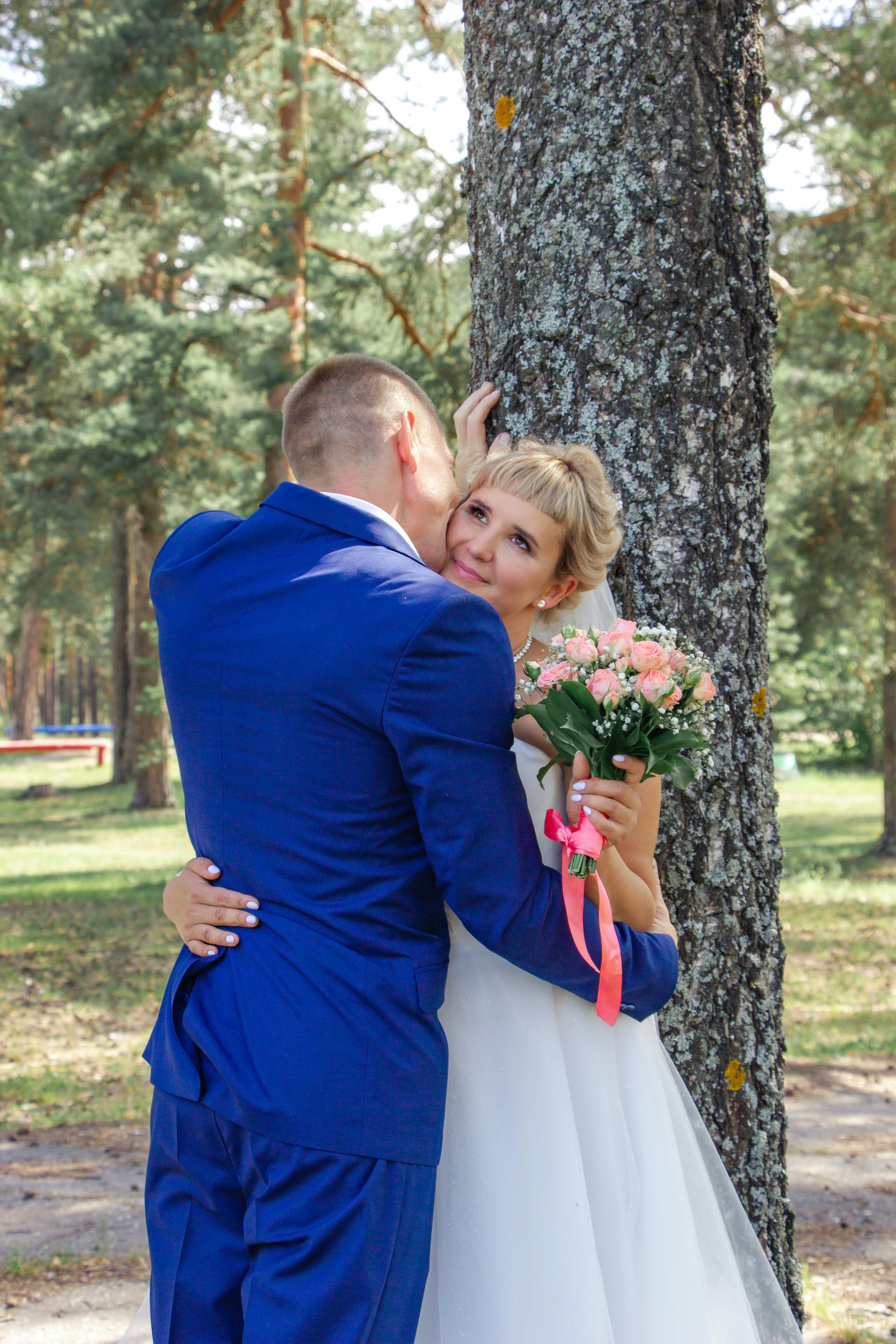 a bride and groom hugging in front of a tree