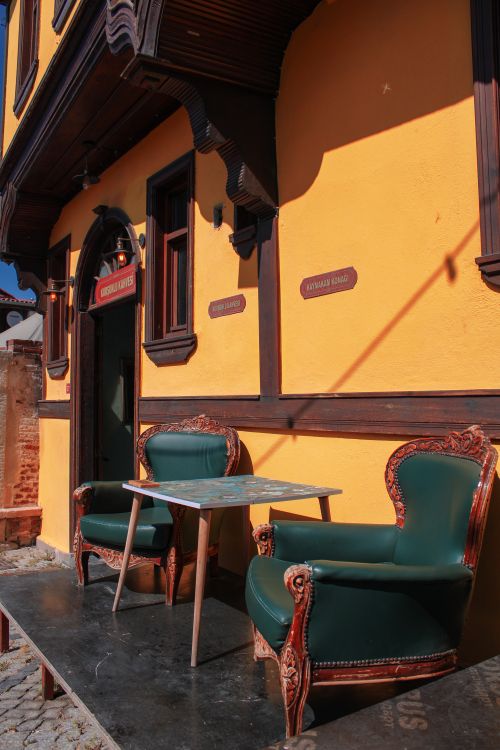 Free Vintage armchairs and table set against a vibrant building exterior in town. Stock Photo