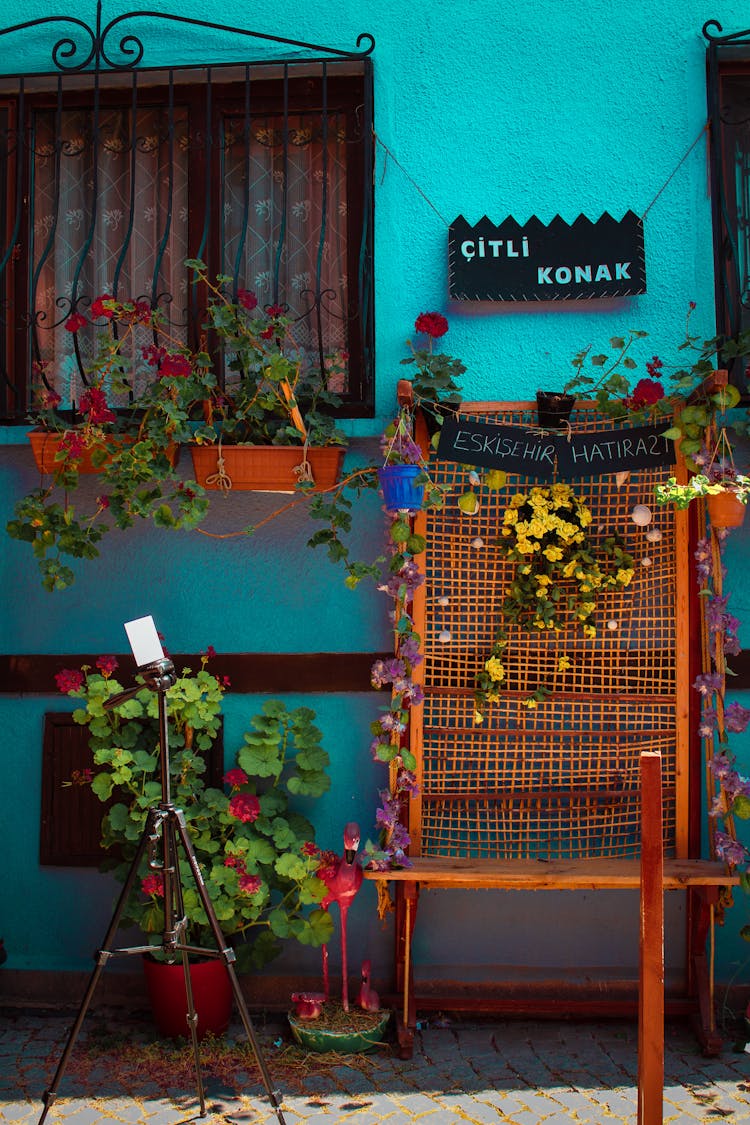 View Of The Exterior Of A Blue Building With Potted Flowers On The Windowsill 