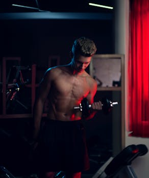 Young man exercising with dumbbells in a gym setting, showcasing strength and fitness.