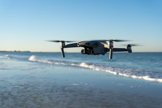 A drone flying over a tranquil beach with gentle waves in the background during sunset.