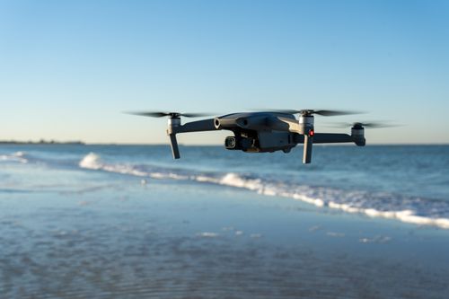 Free A drone flying over a tranquil beach with gentle waves in the background during sunset. Stock Photo