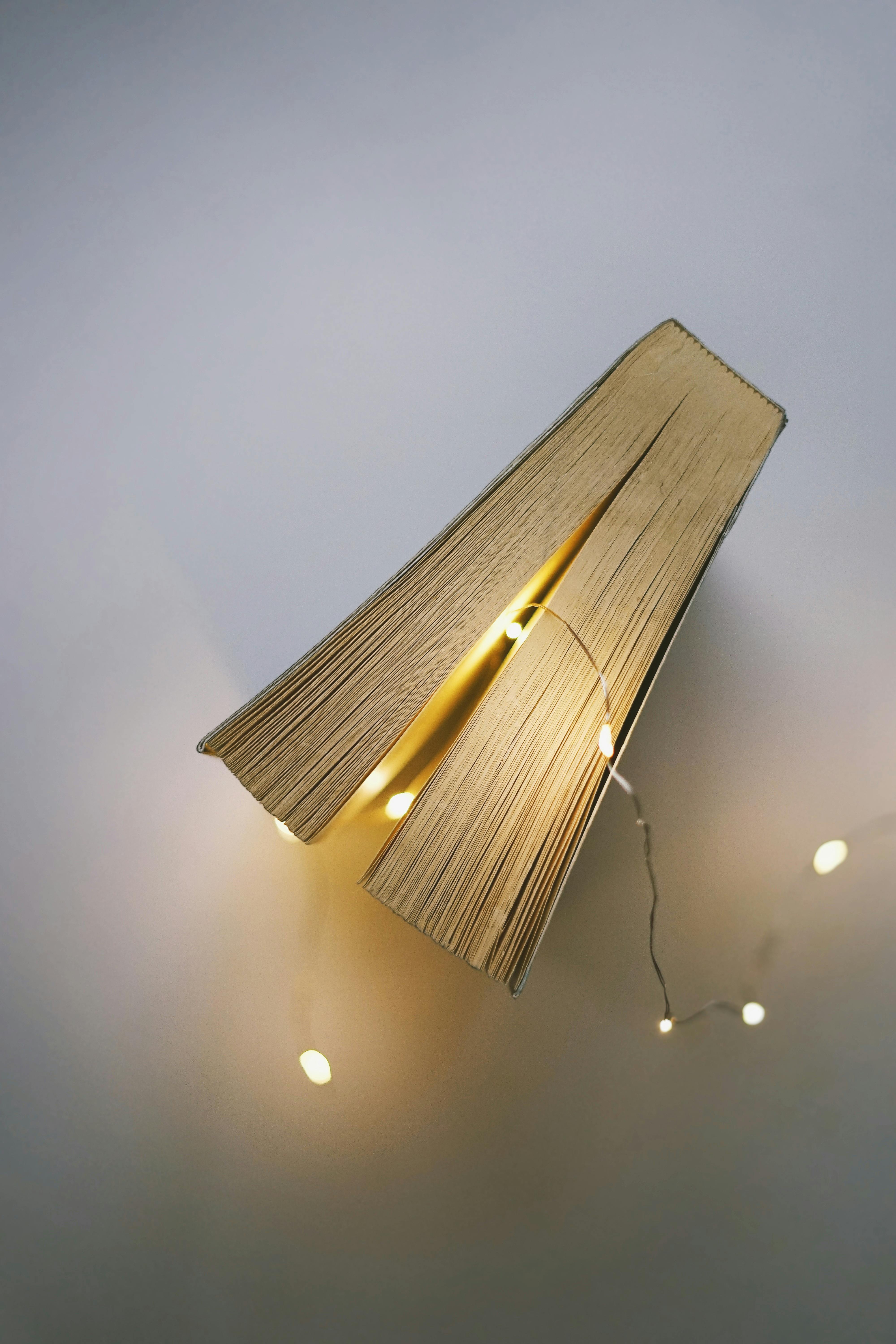 Closed Book Beside Gray String Light on White Surface