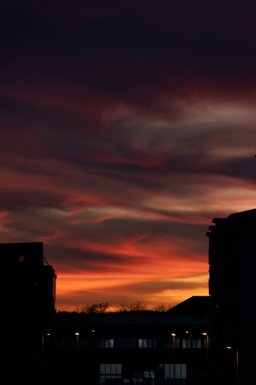 Free Silhouette of urban buildings against a dramatic, colorful sunset sky in Neuhausen am Rheinfall. Stock Photo