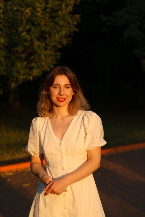 Free Portrait of a woman in a white dress enjoying sunset outdoors. Stock Photo