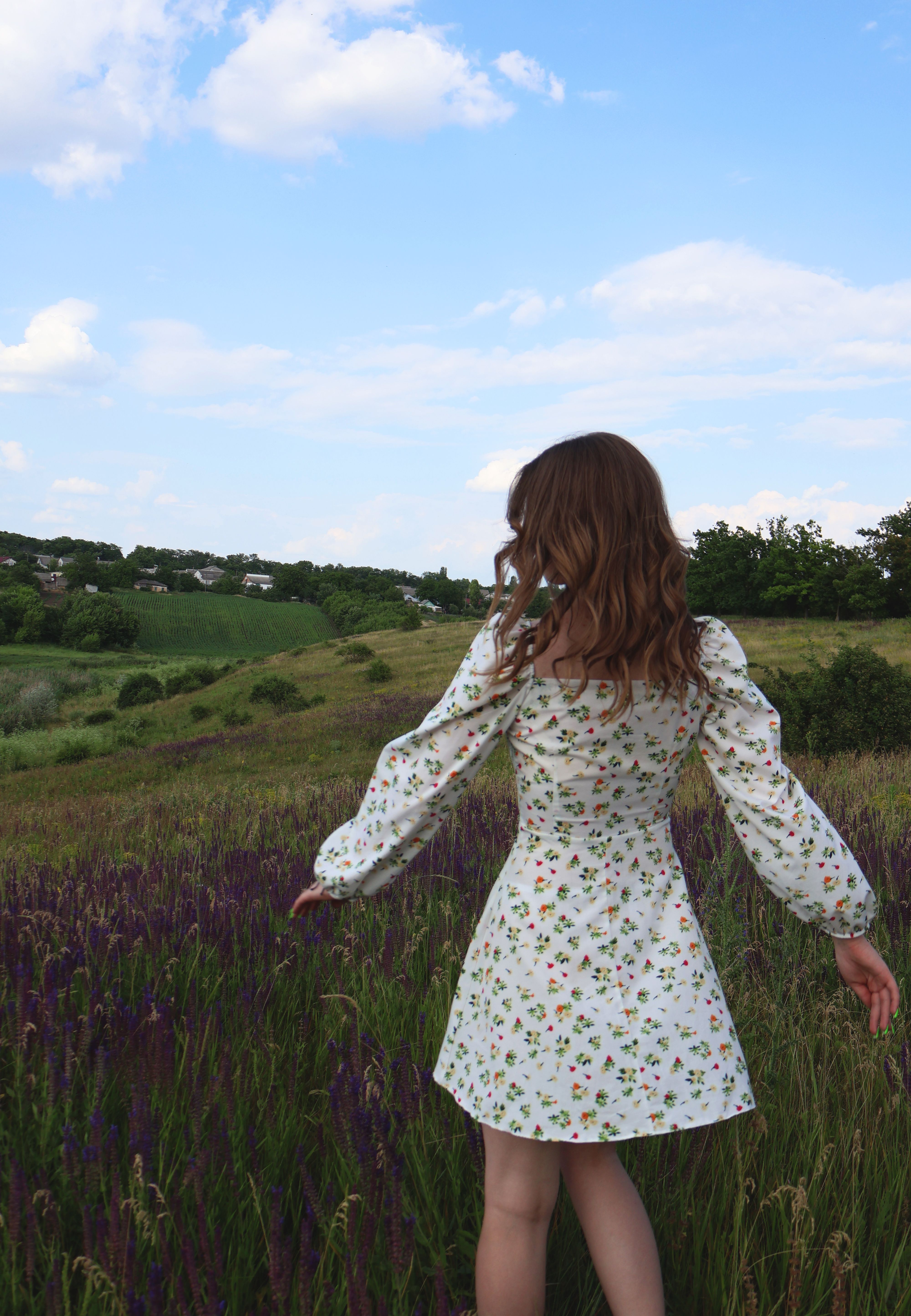 A girl in a white dress is walking through a field · Free Stock Photo