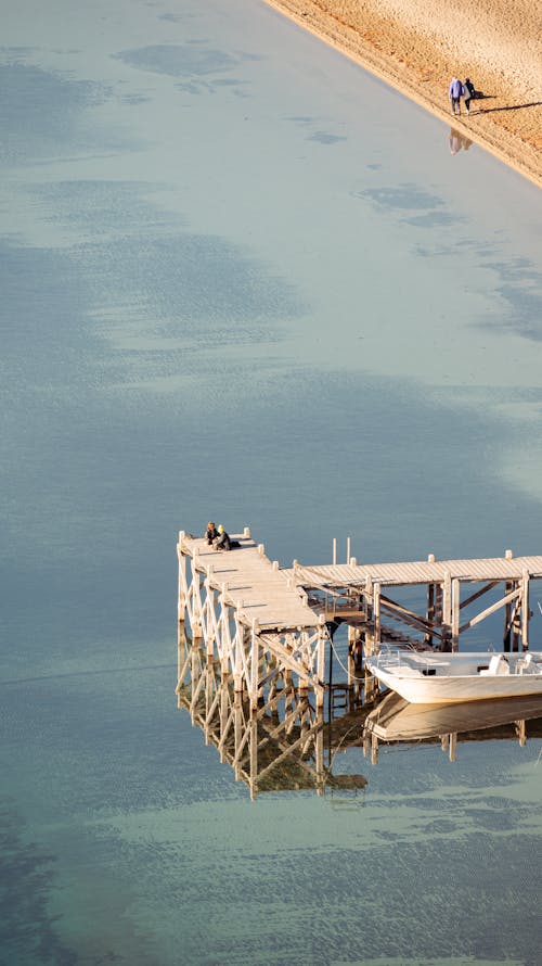 Aerial View of a Pier with a Moored Boat on a Body of Water 