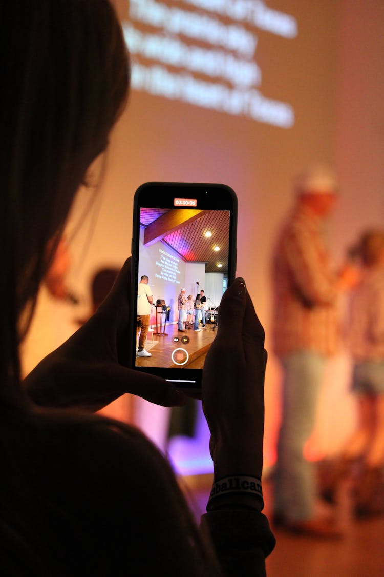 Close-up Of A Woman Recording People On Stage With A Smartphone 