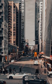 Vibrant city street with skyscrapers, cars, and pedestrians in a bustling urban setting.