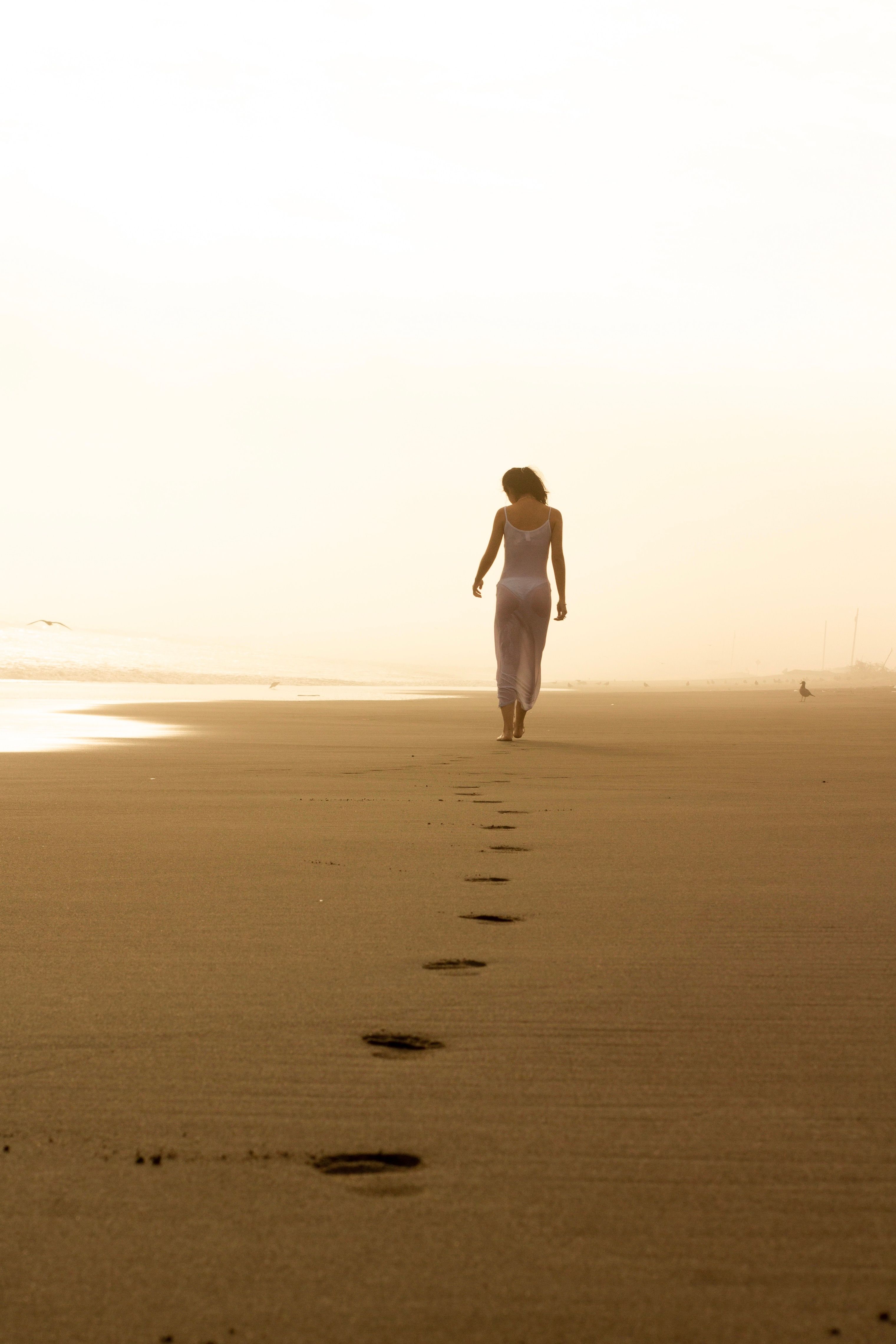 Woman Walking on Beach at Sunset · Free Stock Photo