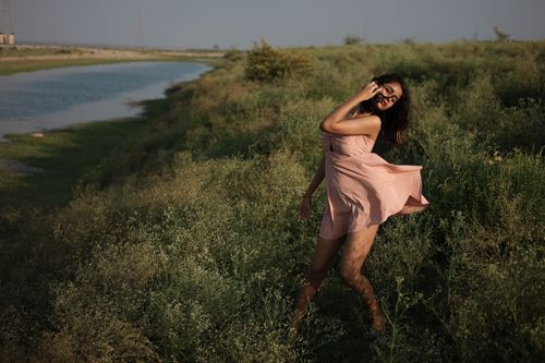 Free Stylish woman in a pink dress poses confidently by a riverbank in Prayagraj, India. Stock Photo