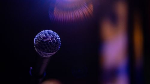 Free A microphone is spotlighted against a dark, blurred background, creating a dramatic atmosphere. Stock Photo