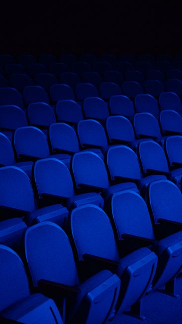 Rows of blue seats in a dark cinema, highlighting an empty theater ambiance.