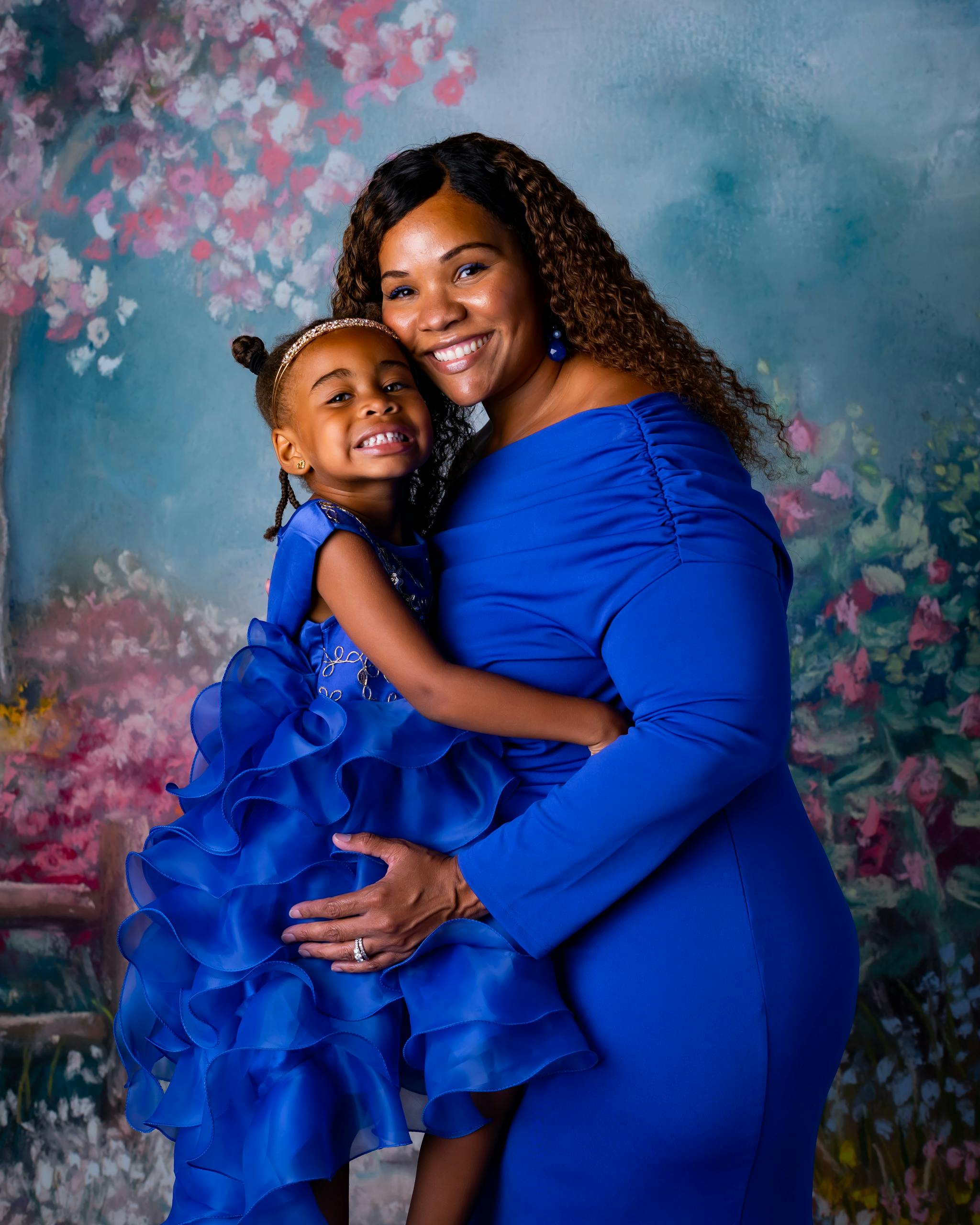 mother and daughter wearing blue dresses hugging and smiling