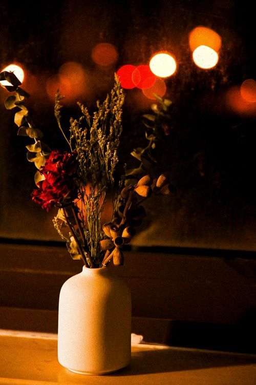 Free Stylish white vase with dried flowers against a blurred night cityscape background. Stock Photo