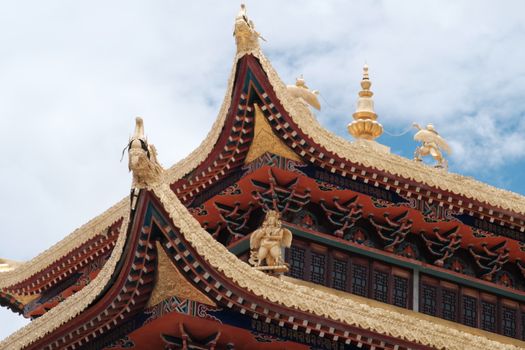 Close-up of a traditional temple rooftop with ornate details against a blue sky.