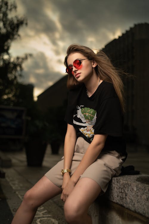 Woman in Sunglasses Sitting on Wall