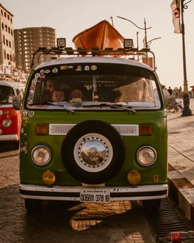 A classic green camper van parked on a city street during sunset, capturing a nostalgic travel vibe.