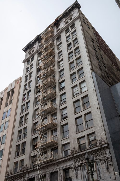 Free A tall city building with a classic fire escape ladder, representing urban architecture. Stock Photo
