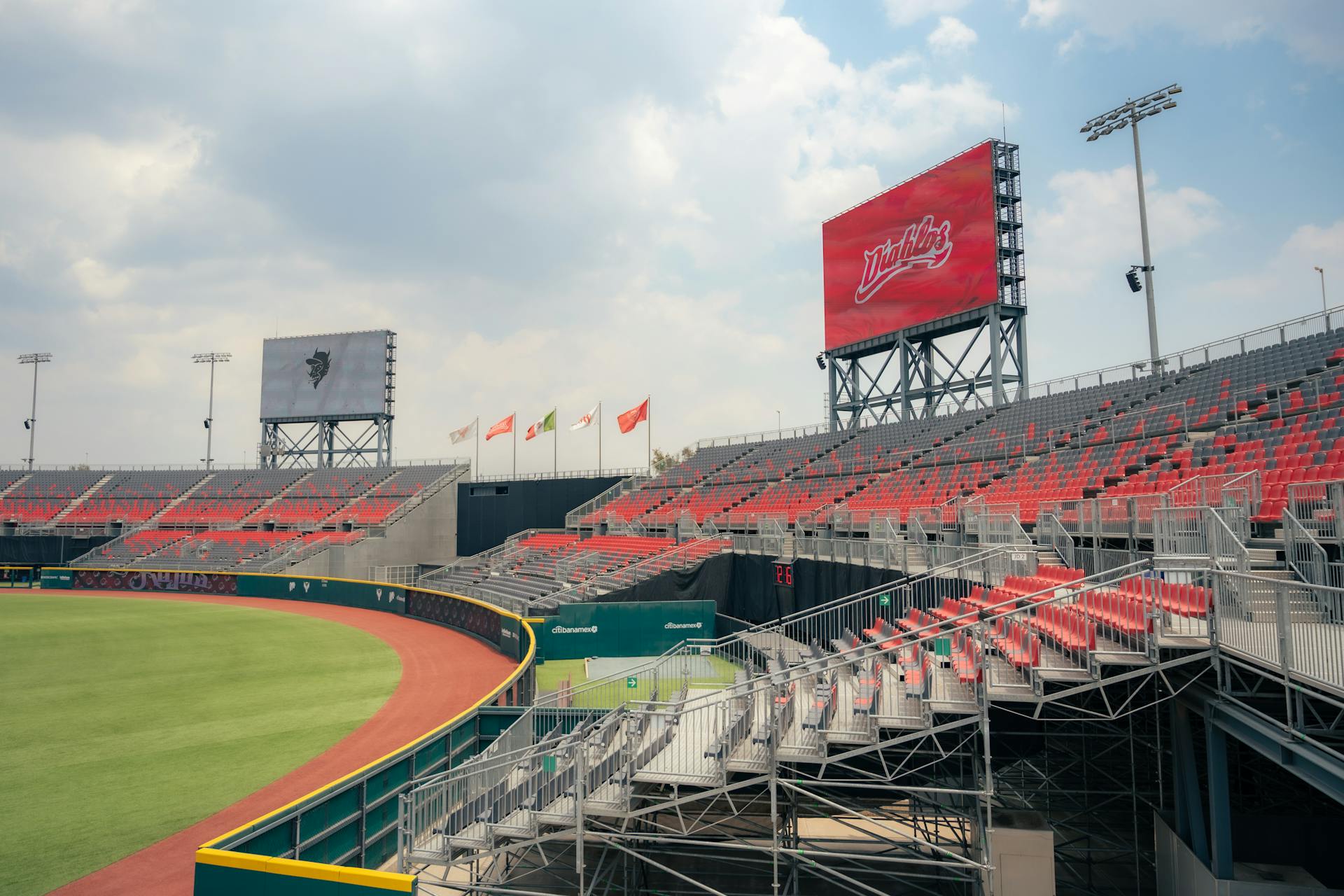 A baseball stadium with red seats and a scoreboard