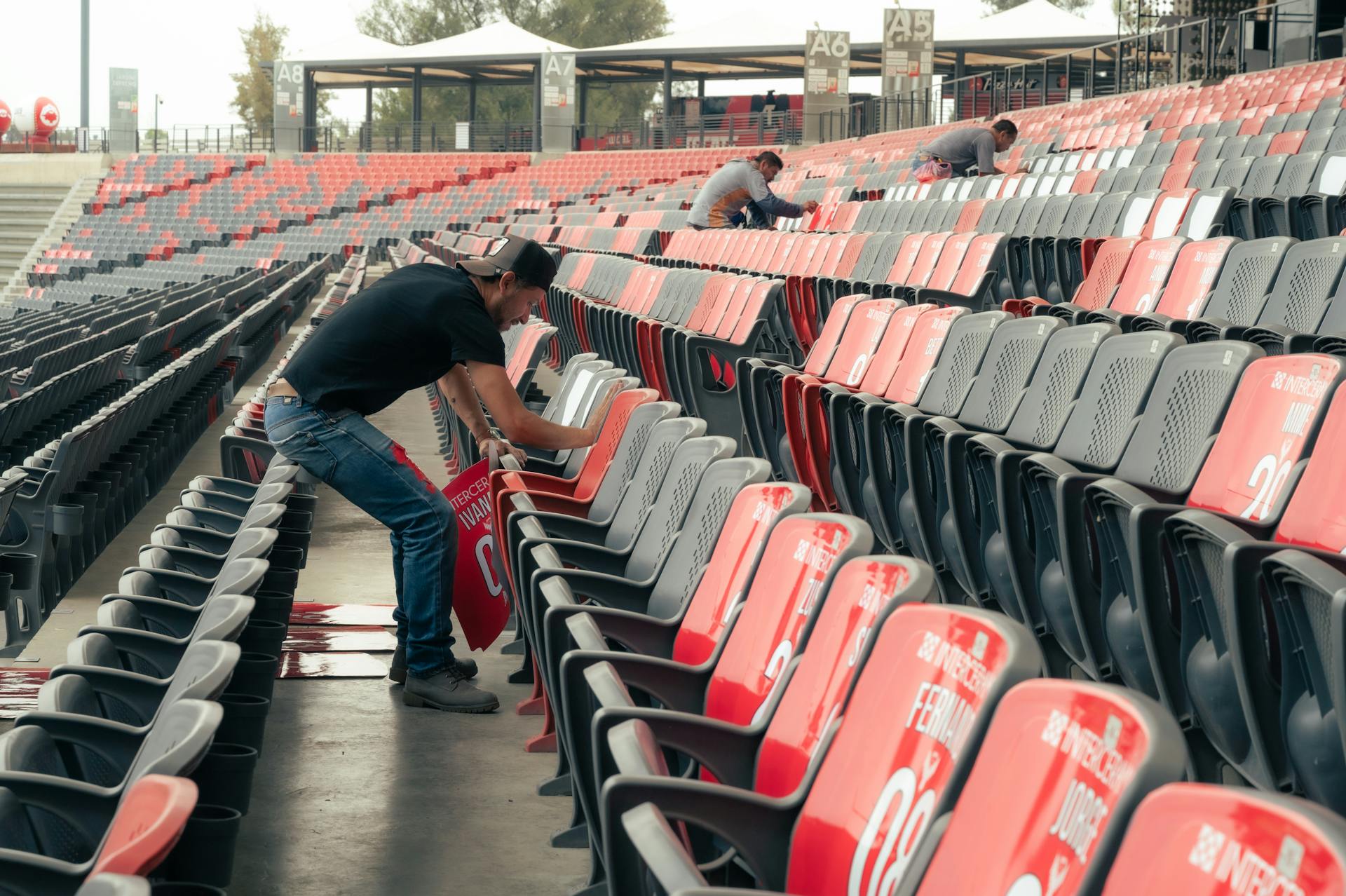 A man is working on the seats in a stadium