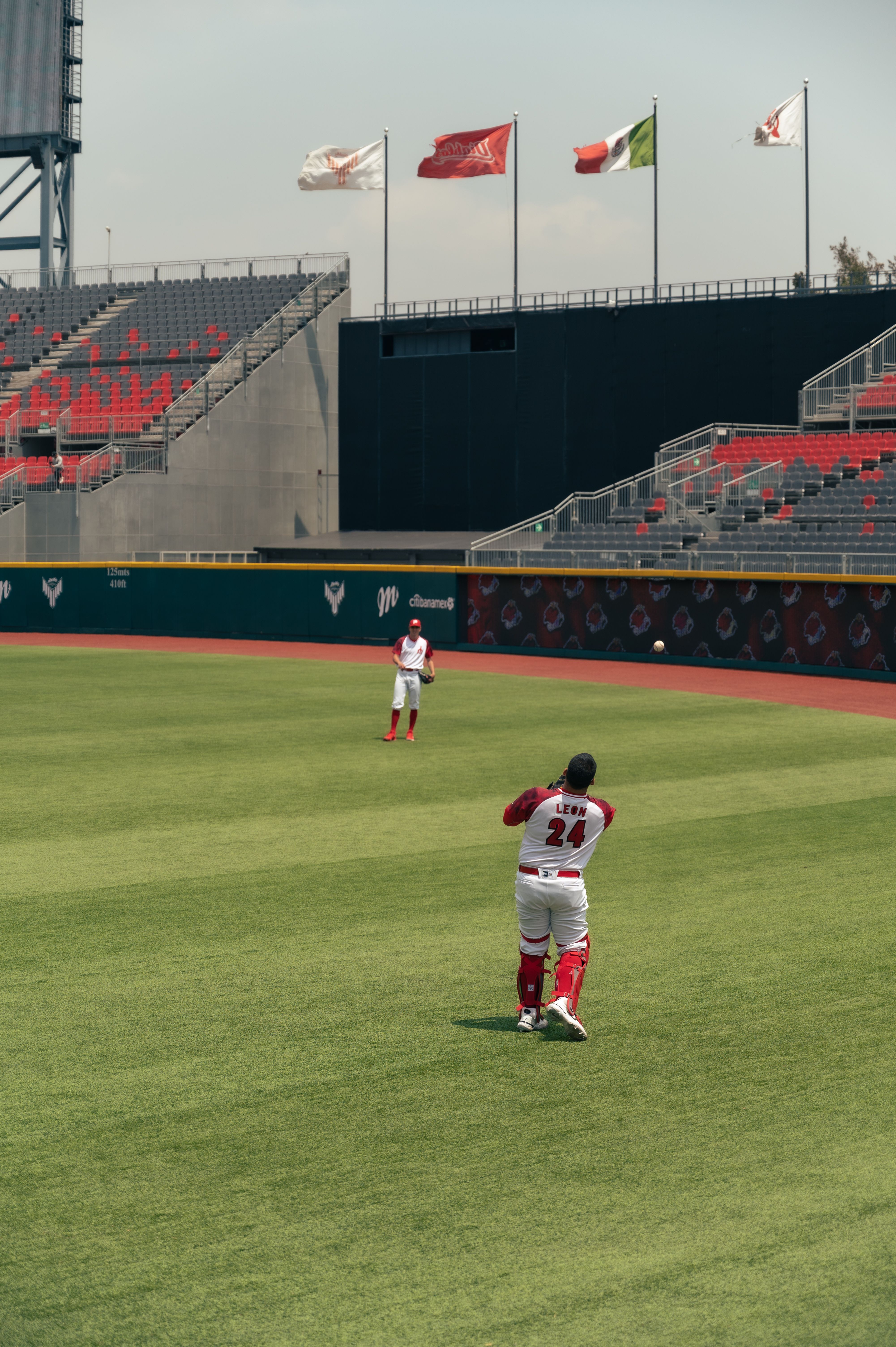Baseball players practicing on a sunny day in a modern stadium.