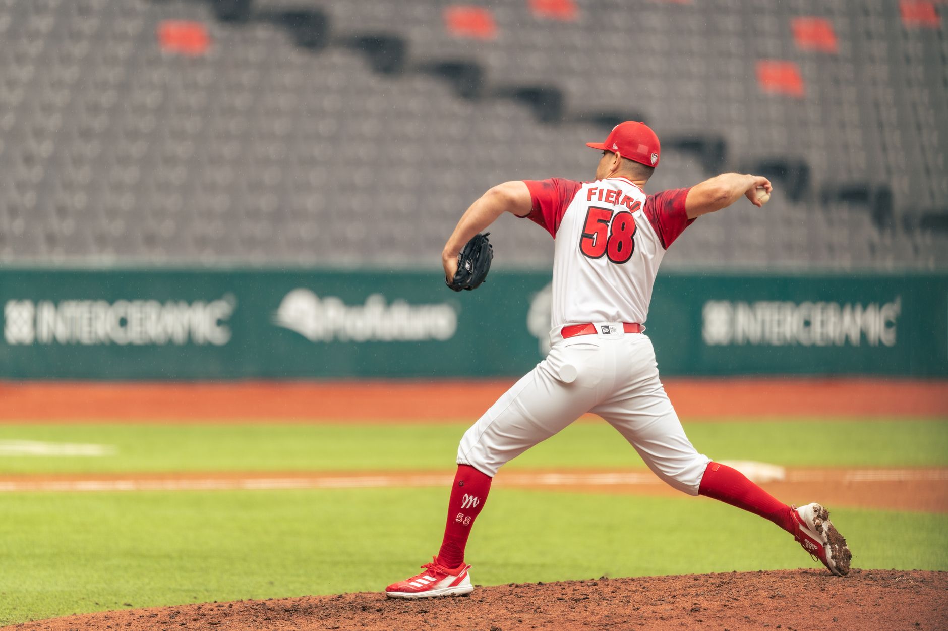 Dynamic shot of a baseball pitcher in action on a stadium mound wearing a red and white uniform.