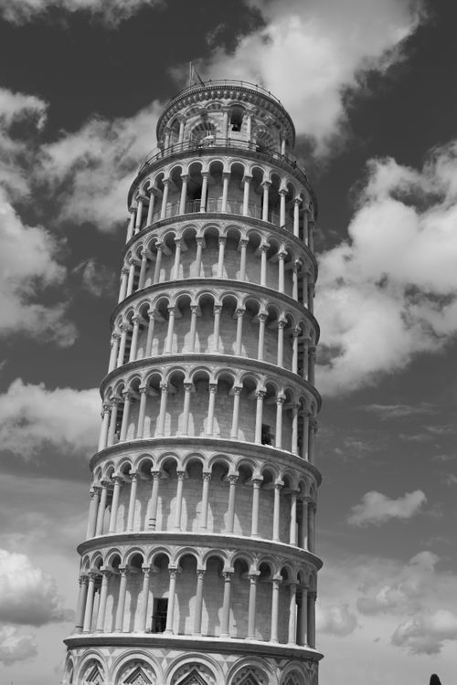 Free Dramatic black and white shot of the Leaning Tower of Pisa against a cloudy sky. Stock Photo