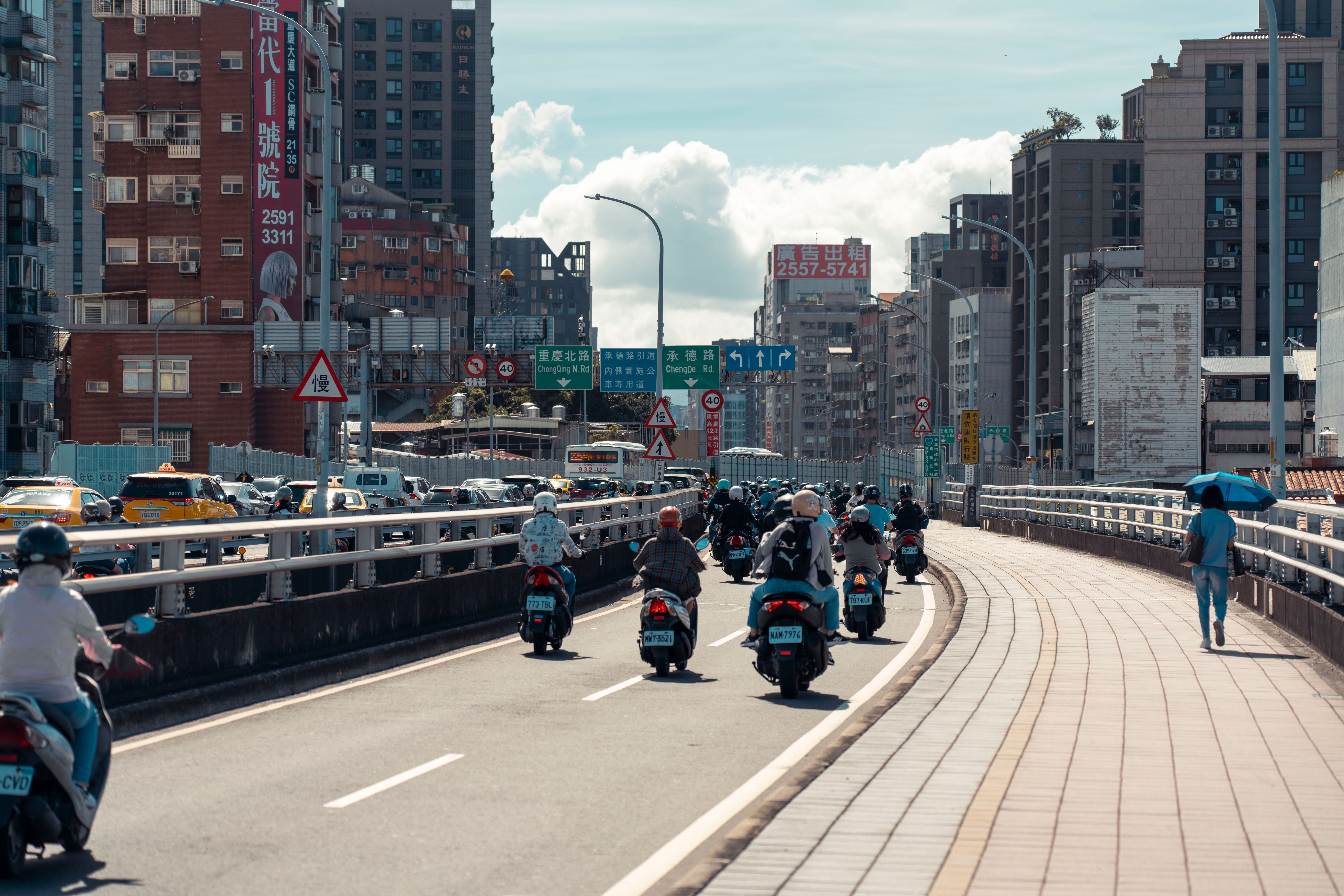 A group of people riding motorcycles on a city street · Free Stock Photo