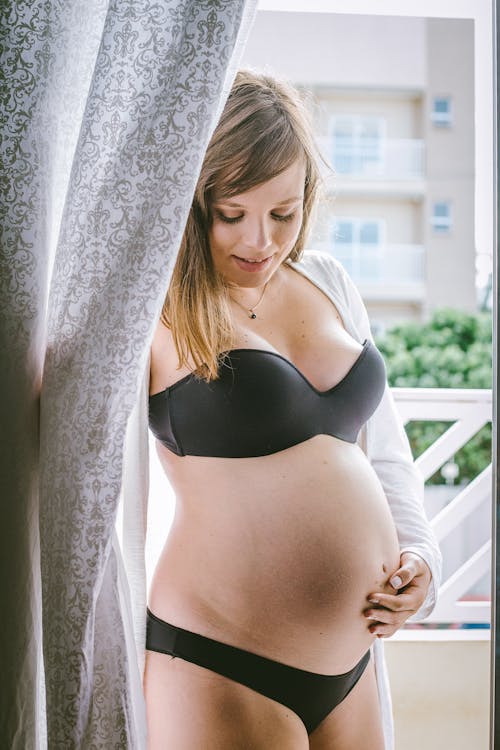 Young pregnant woman in black underwear on balcony