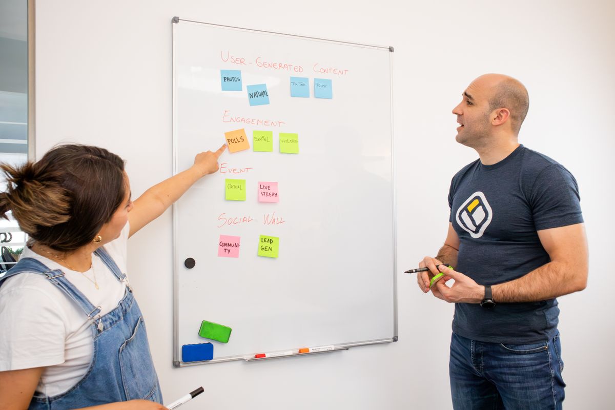 Woman and man planning marketing channels on a whiteboard with sticky notes