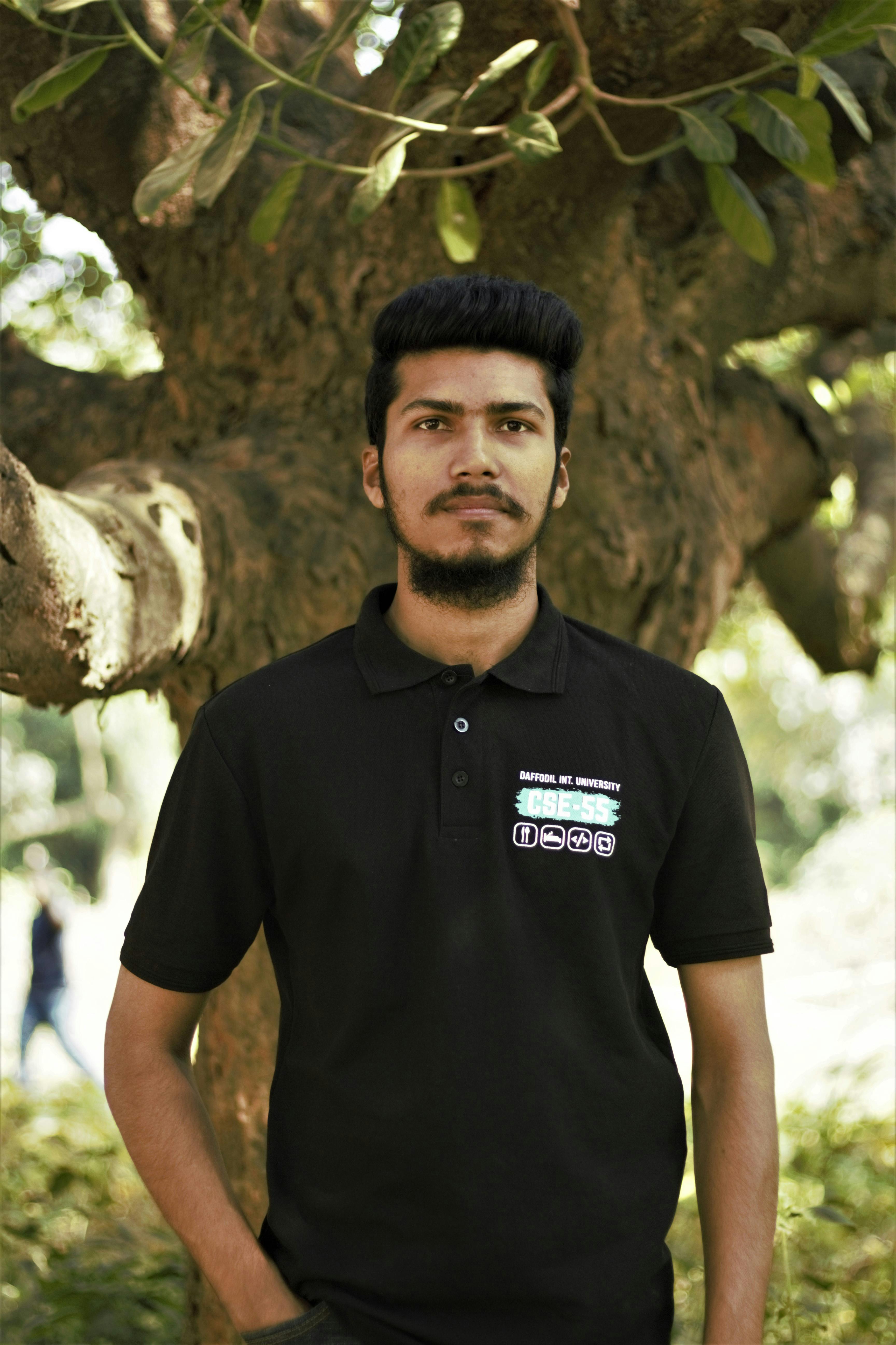 Young man standing outdoors in Ashulia Model Town, Dhaka on a sunny day.