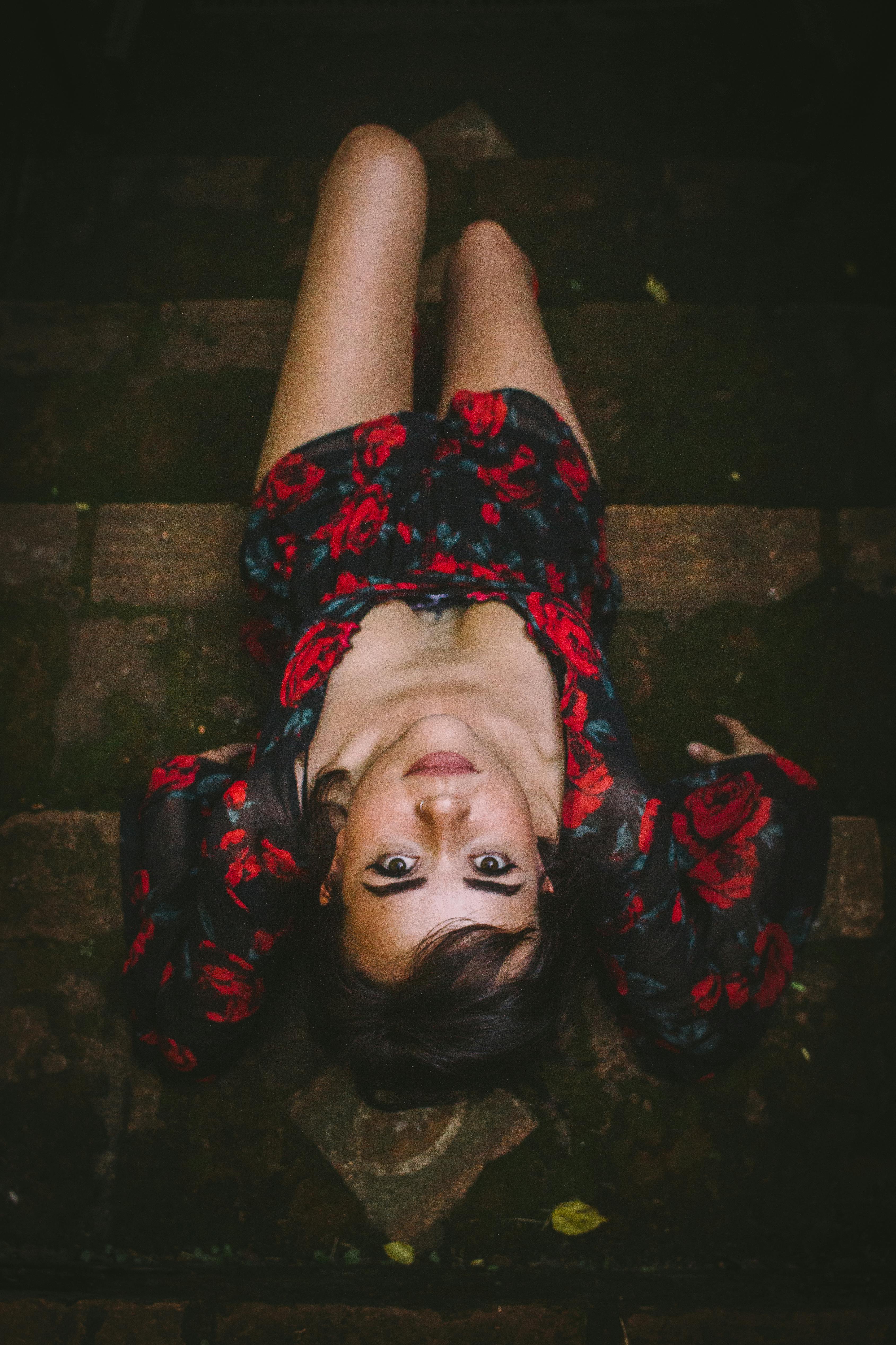 Portrait of a woman in a floral dress lying on steps, viewed from above.