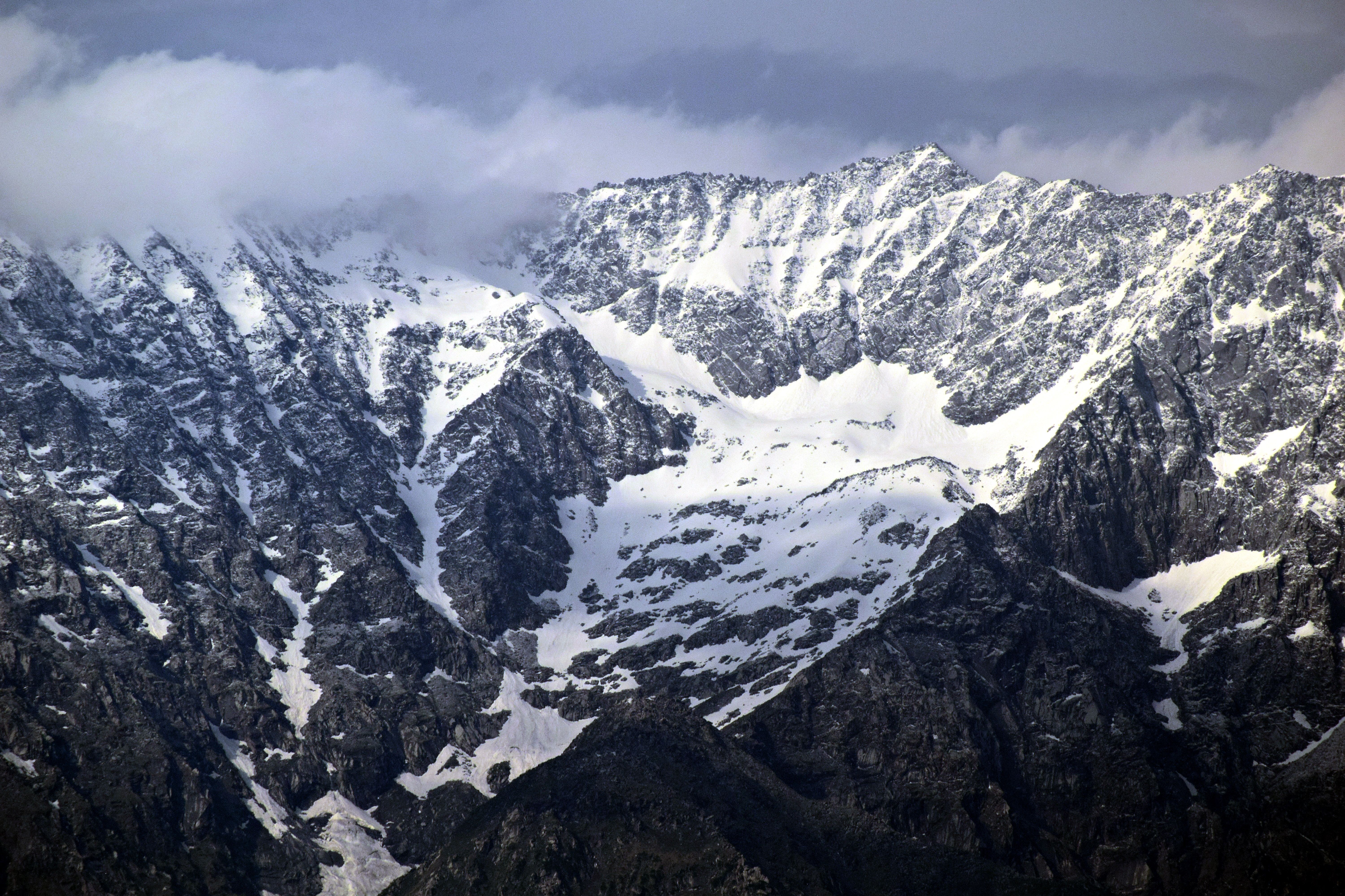A snow covered mountain range with clouds in the sky · Free Stock Photo