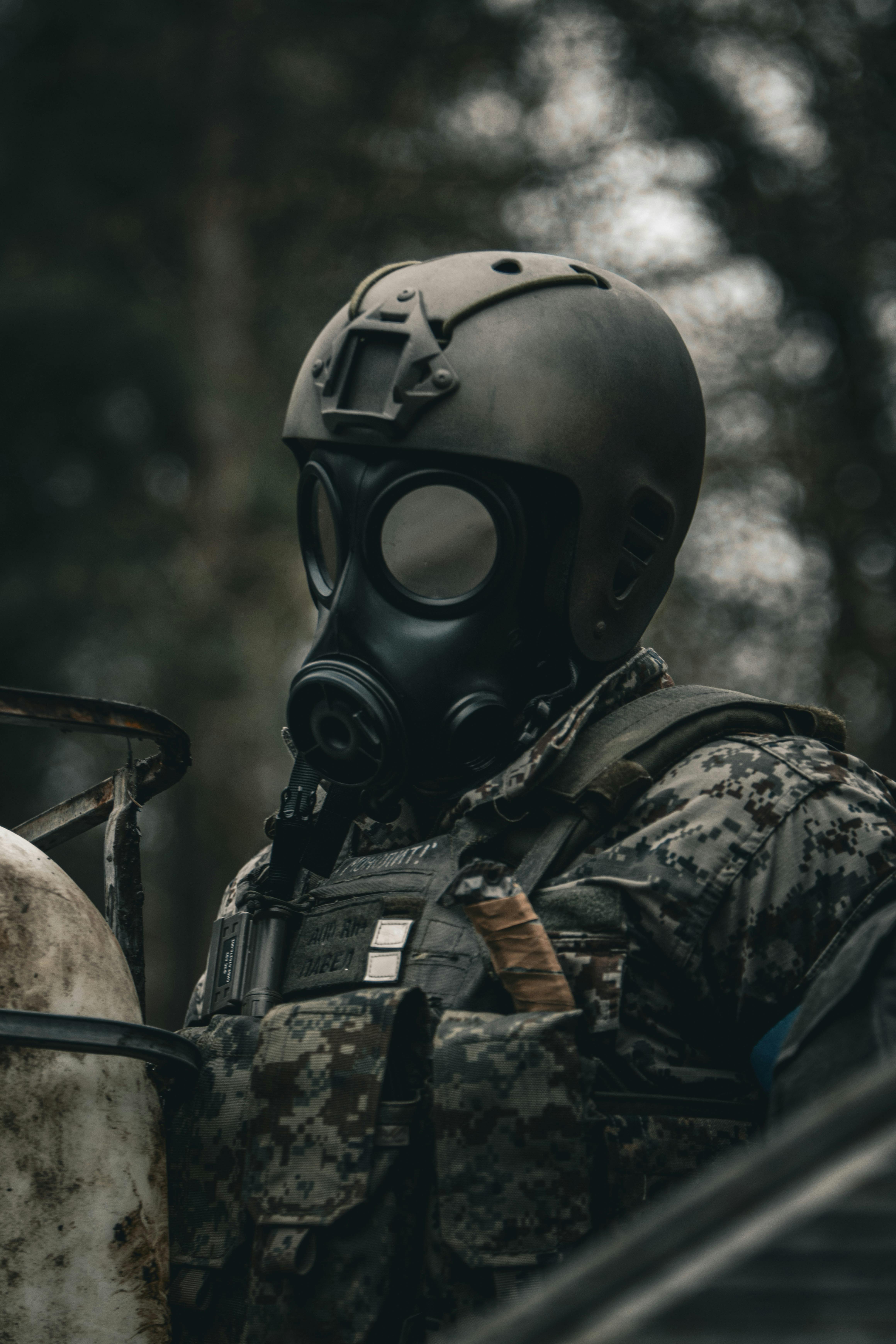 A soldier in a gas mask standing next to a vehicle